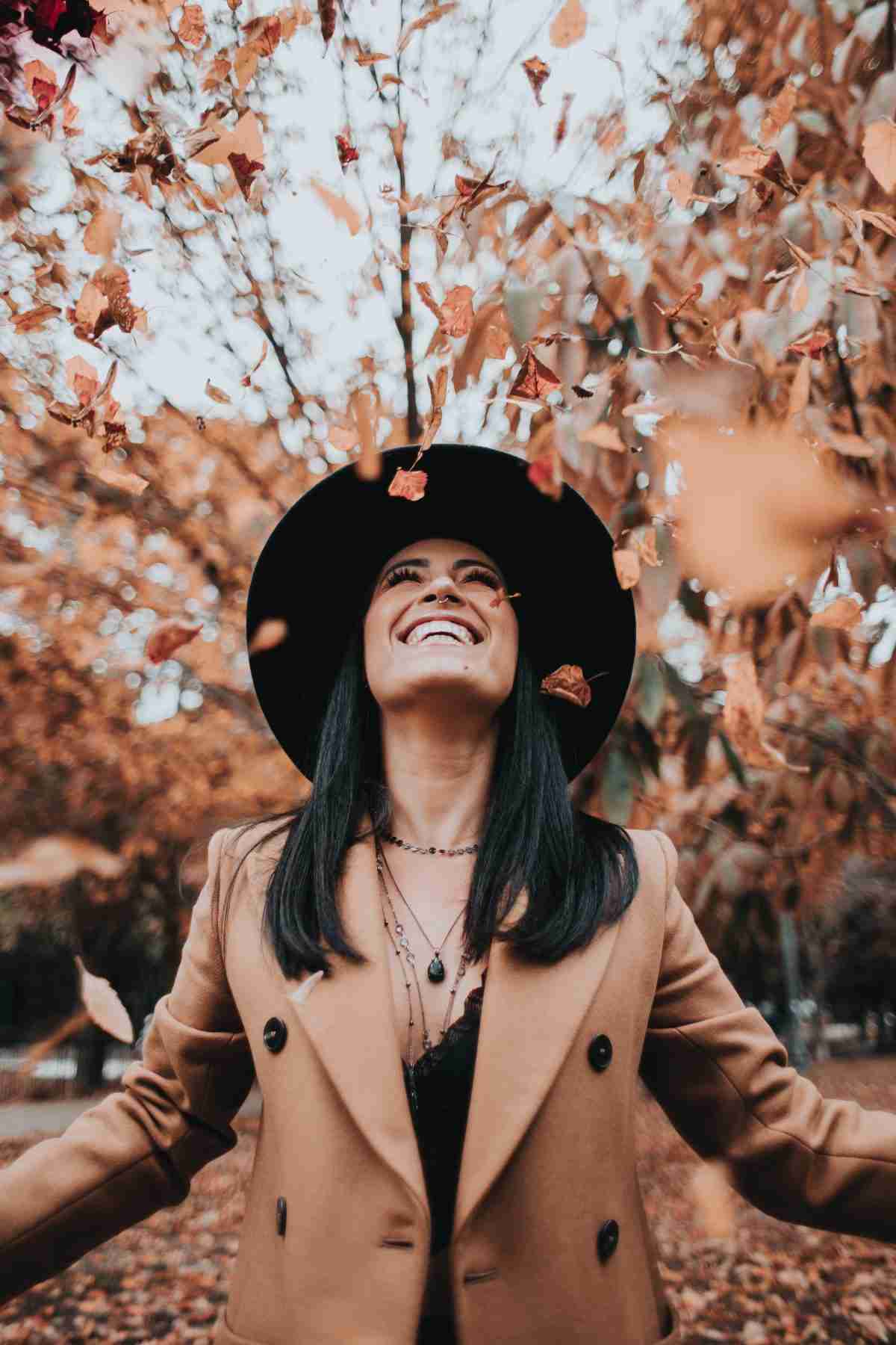 Immagine di donna sorridente in mezzo un bosco autunnale per l'articolo L'autunno ti rende triste?