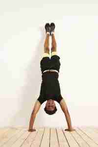 uomo in piedi a testa in giù sorridente per l'articolo Crossfit: Hand stand hold, l'esercizio che sveglia più del caffè​