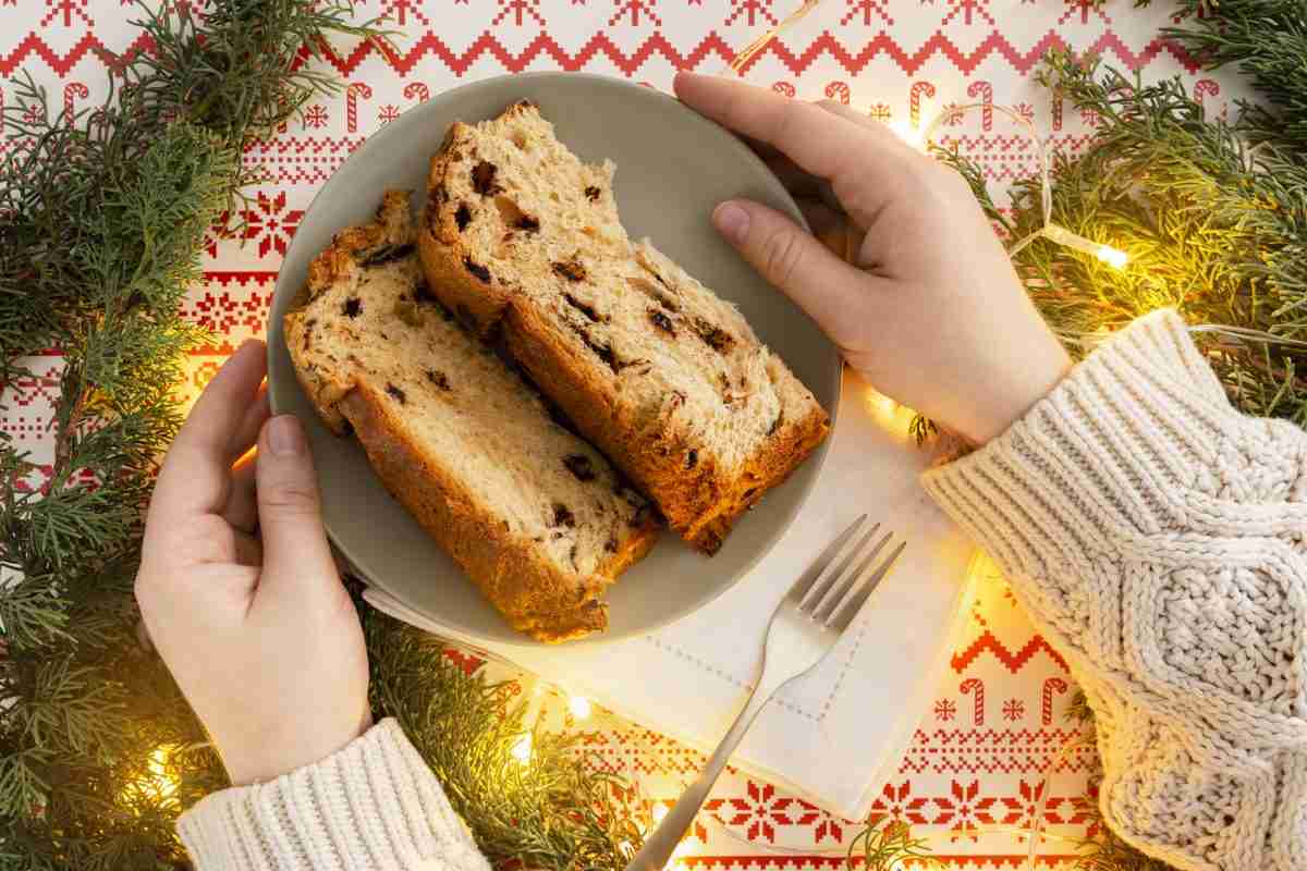 fetta di panettone su piatto e mani di donna per articolo Come usare i dolci avanzati di Natale in modo sano e equilibrato? Scopri le strategie migliori per gustarli senza rovinare salute e linea.