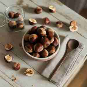 Immagine di tavolo con castagne cotte e crude per l'articolo "Castagne: proprietà, benefici e idee sane per gustarla tutto l'anno"